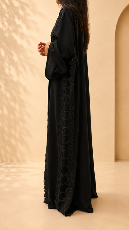 Abaya Meraas noire vue de trois quarts, coupe ample et évasée