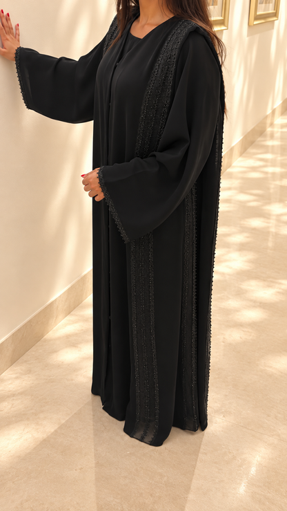 Détail des bandes verticales de dentelle guipure perlée de l'abaya Umm Suqeim noire