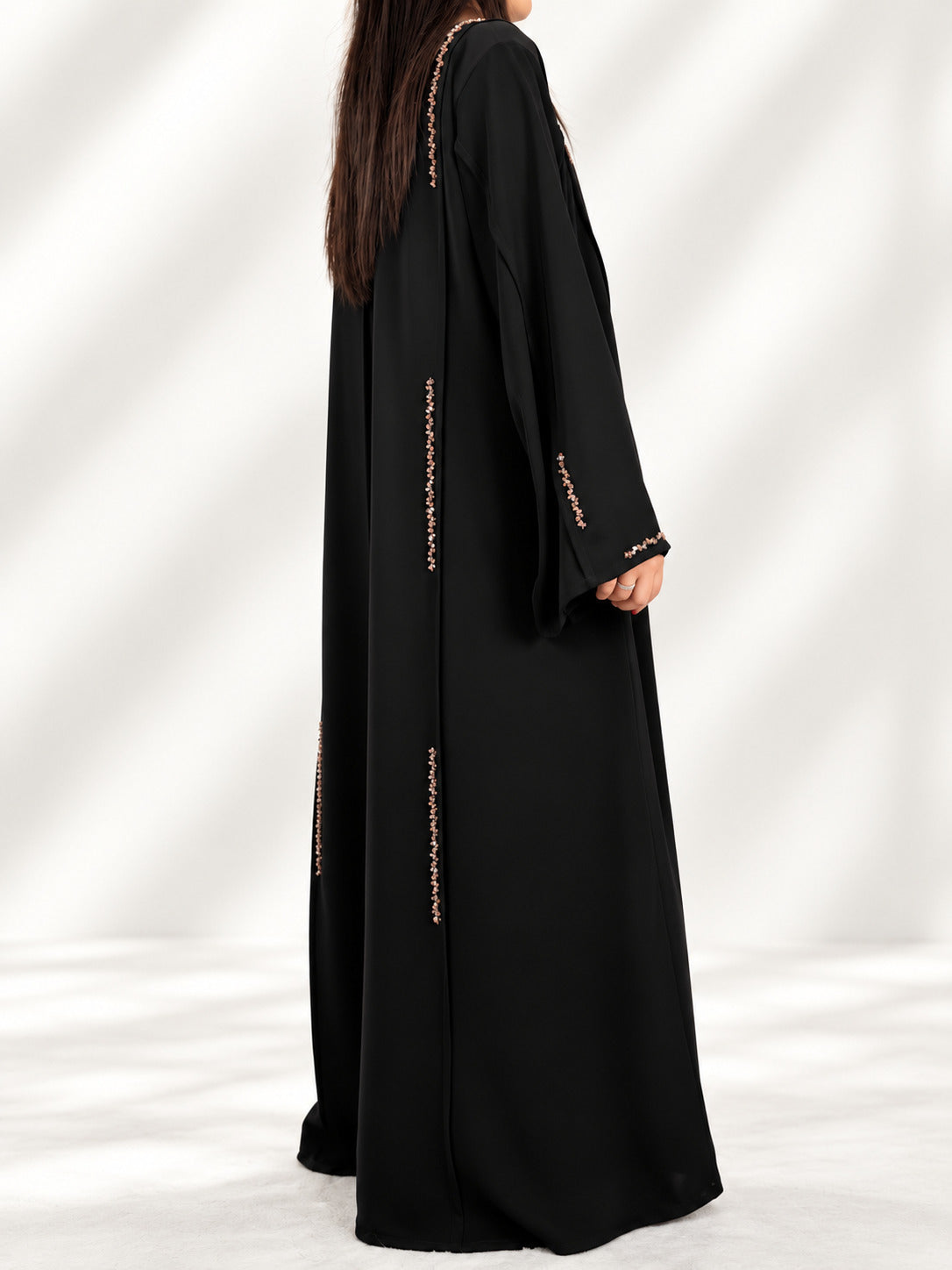 Abaya Nimat noire de dos en trois quarts, cristaux dorés sur l'épaule
