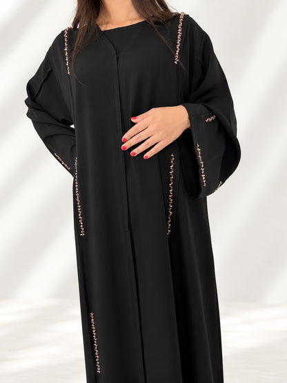 Buste de l'abaya Nimat noire, galons de cristaux dorés le long des coutures